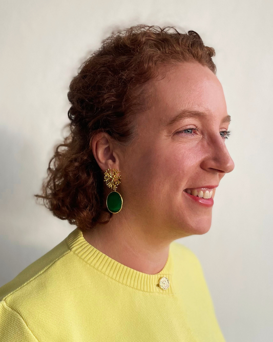 Lina lleva los pendientes Coralina. Coralina dorada con colgante de piedra verde.