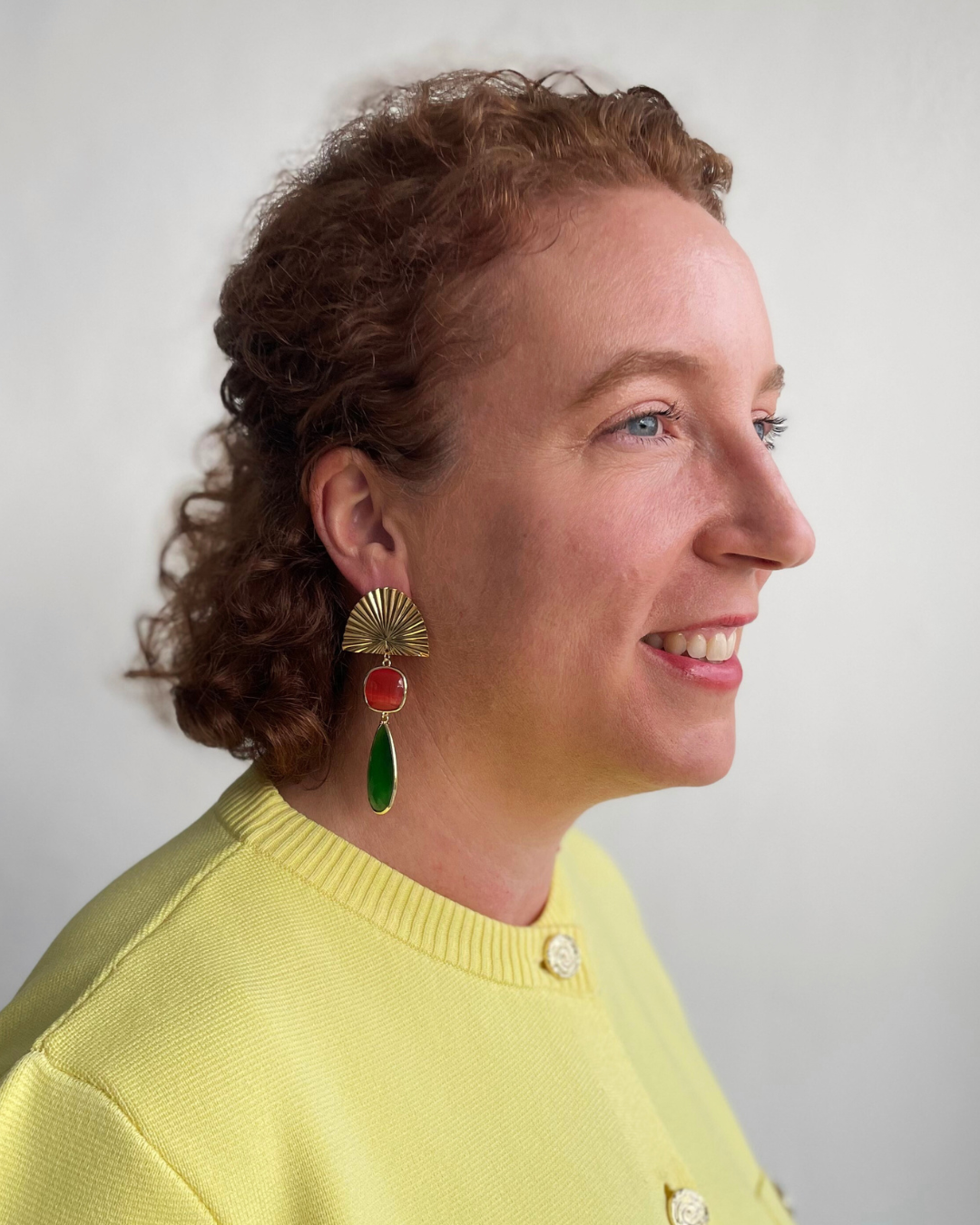 Lina lleva los pendientes Bailar de Luz. Bailar de Luz dorada con colgante de piedra naranja y verde.