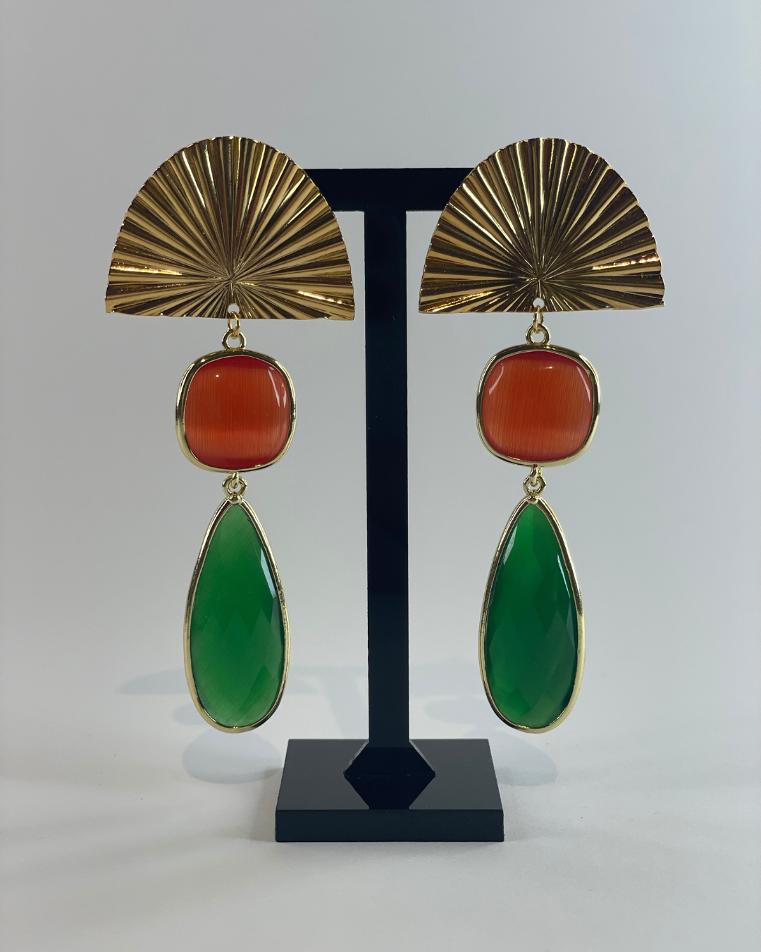 Vista frontal de los pendientes Bailar de Lu. El pendiente tiene un cierre de oro y dos piedras en verde y naranja como colgante.