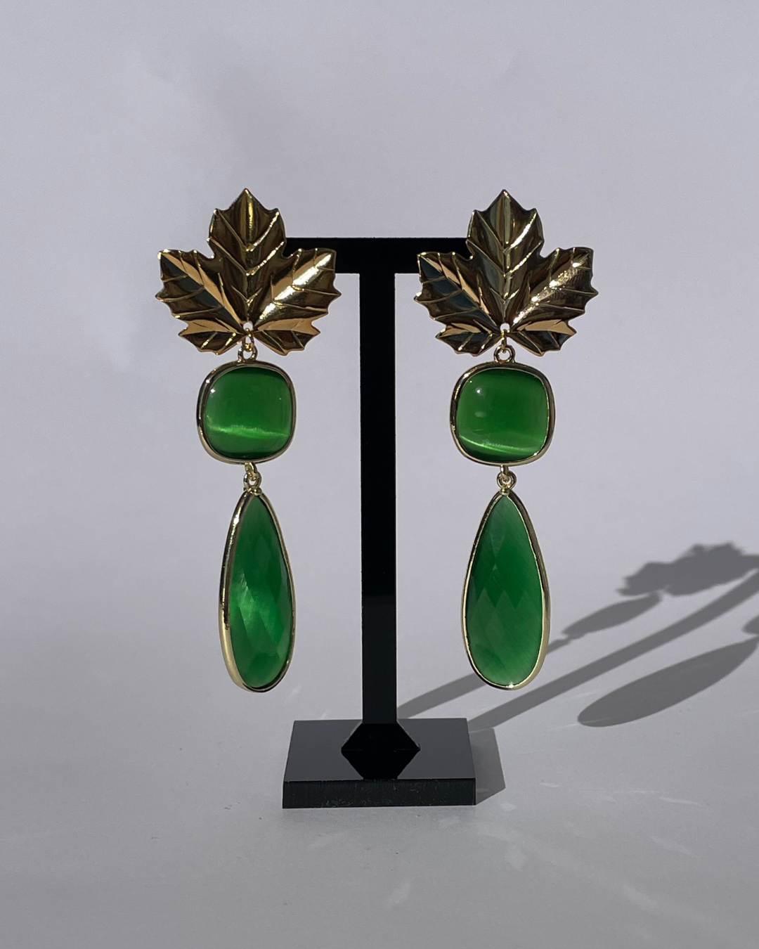 Brillo Otonal -el pendiente tiene un cierre de oro y dos piedras verde como colgante.