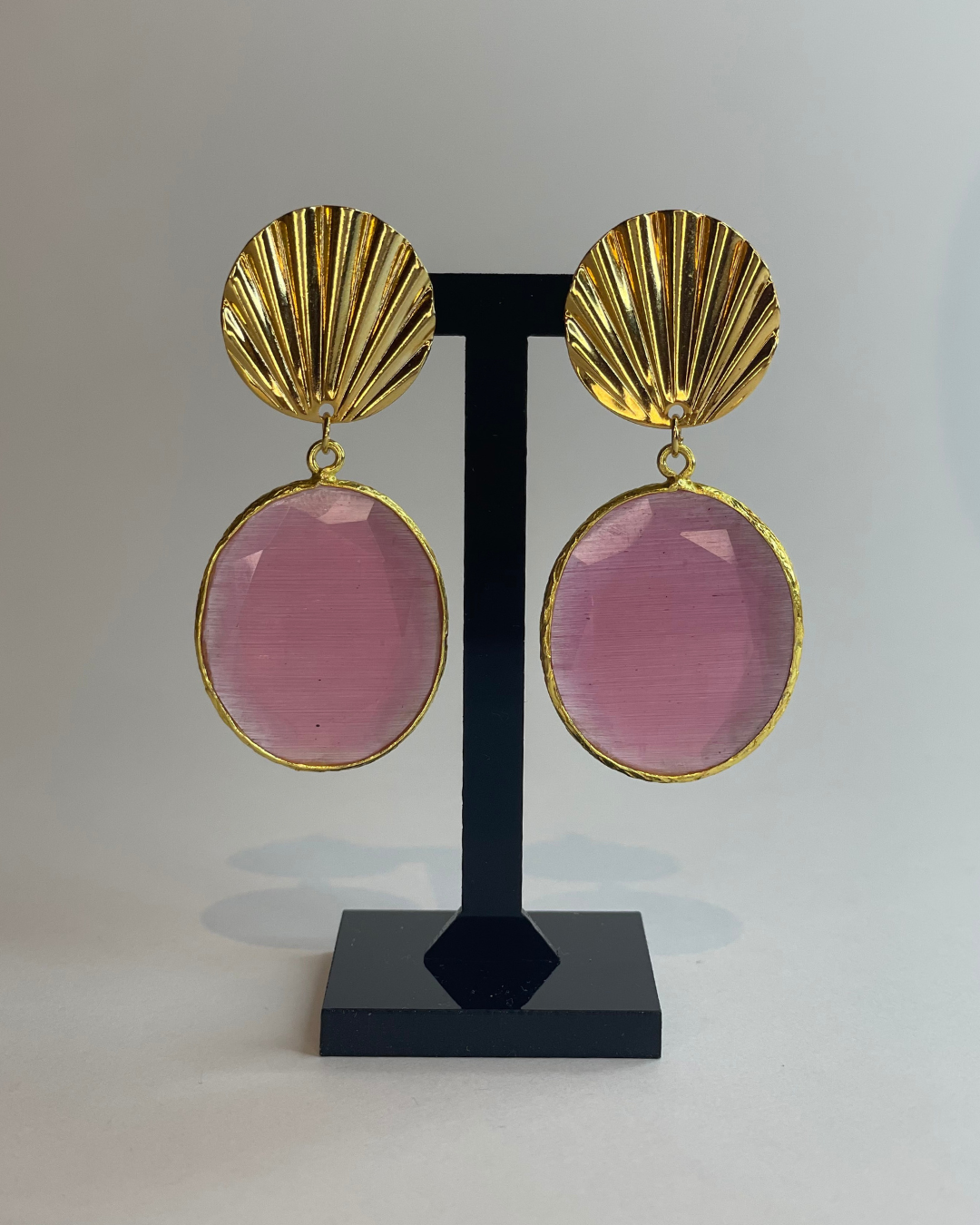 Vista frontal de los pendientes Conach. El pendiente tiene un cierre de oro y una piedra rosa como colgante.