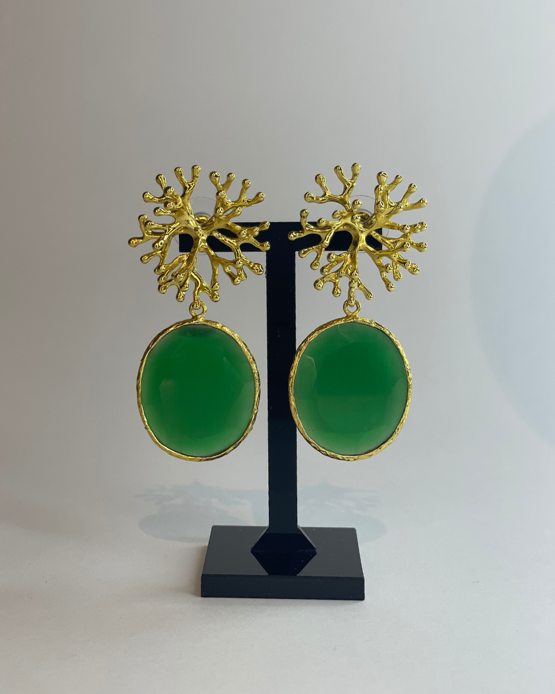 Vista frontal de los pendientes Coralina. El pendiente tiene un cierre de oro y una piedra verde como colgante.