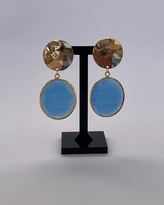 Espejo de Cielo - el pendiente tiene un cierre de oro y una piedra azul como colgante.