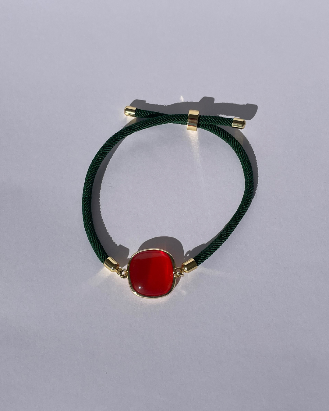 la pulsera verde con piedra naranja.