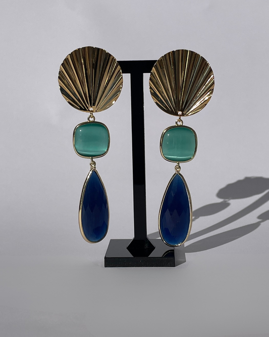 Vista frontal de los pendientes Tesoro Marino. El pendiente tiene un cierre de oro y dos piedras azul como colgante.